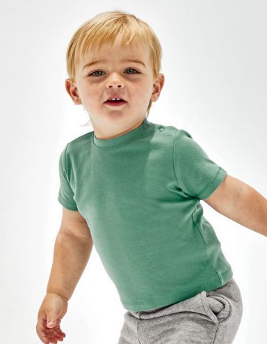 Junge in grünem T-Shirt und grauen Shorts, lächelt und schaut in die Kamera.