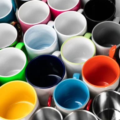 Vielfältige Tassen in verschiedenen Farben und Materialien, dicht beieinander angeordnet.