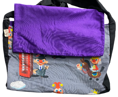Schultertasche mit buntem Druck von Comicfiguren und lila Klappe.