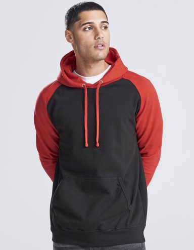 Junger Mann trägt einen schwarzen Hoodie mit roten Ärmeln und schaut nachdenklich.