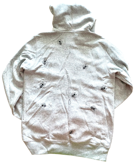 Grauener Kapuzenpullover mit floralem Muster auf dem Rücken.
