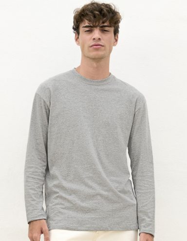 Junger Mann in grauem Langarmshirt vor neutralem Hintergrund.