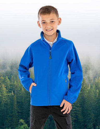 Junge trägt eine blaue Jacke und steht vor einem nebligen Waldhintergrund.