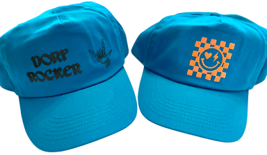 Zwei türkisfarbene Caps, eines mit "DORF ROCKER" und das andere mit einem Smiley-Motiv.
