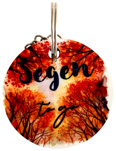 Runder Schlüsselanhänger mit herbstlichem Baumdesign und der Aufschrift „Segen to go“.