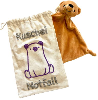 Weißer Sack mit der Aufschrift „Kuschel Notfall“ und einem braunen Schmuse-Tuch mit Bärenkopf.