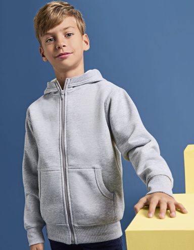 Junge mit kurzem blondem Haar trägt einen grauen Kapuzenpulli und lächelt.