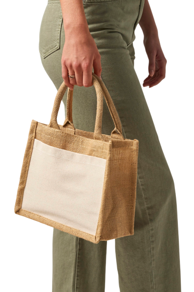 Braune Handtasche aus Jute mit weißen Seiten, getragen von einer Person in grüner Hose.