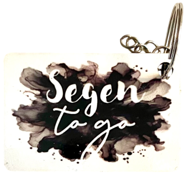 Schlüsselanhänger mit dem Schriftzug "Segen to go" auf schwarzem, aquarellartigem Hintergrund.