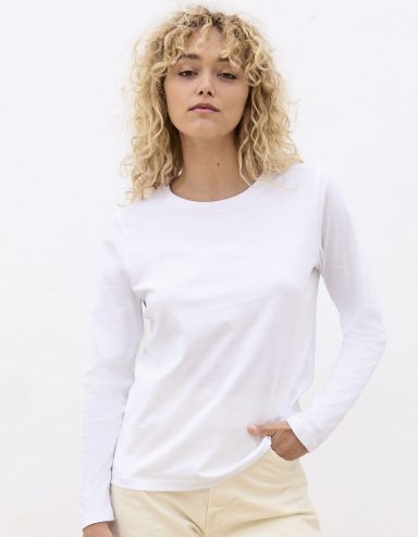 Frau mit lockigem blondem Haar trägt ein weißes Langarmshirt.